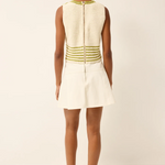 Woman wearing a white dress with green accents on a plain background