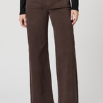 A model wearing a pair of dark brown wide-leg corduroy pants, styled with a black long-sleeve top and black leather clogs, against a light gray studio background.