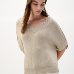 Woman wearing a beige knit top on a white background