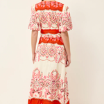 Woman wearing a red and white patterned dress on a plain background