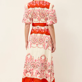 Woman wearing a red and white patterned dress on a plain background