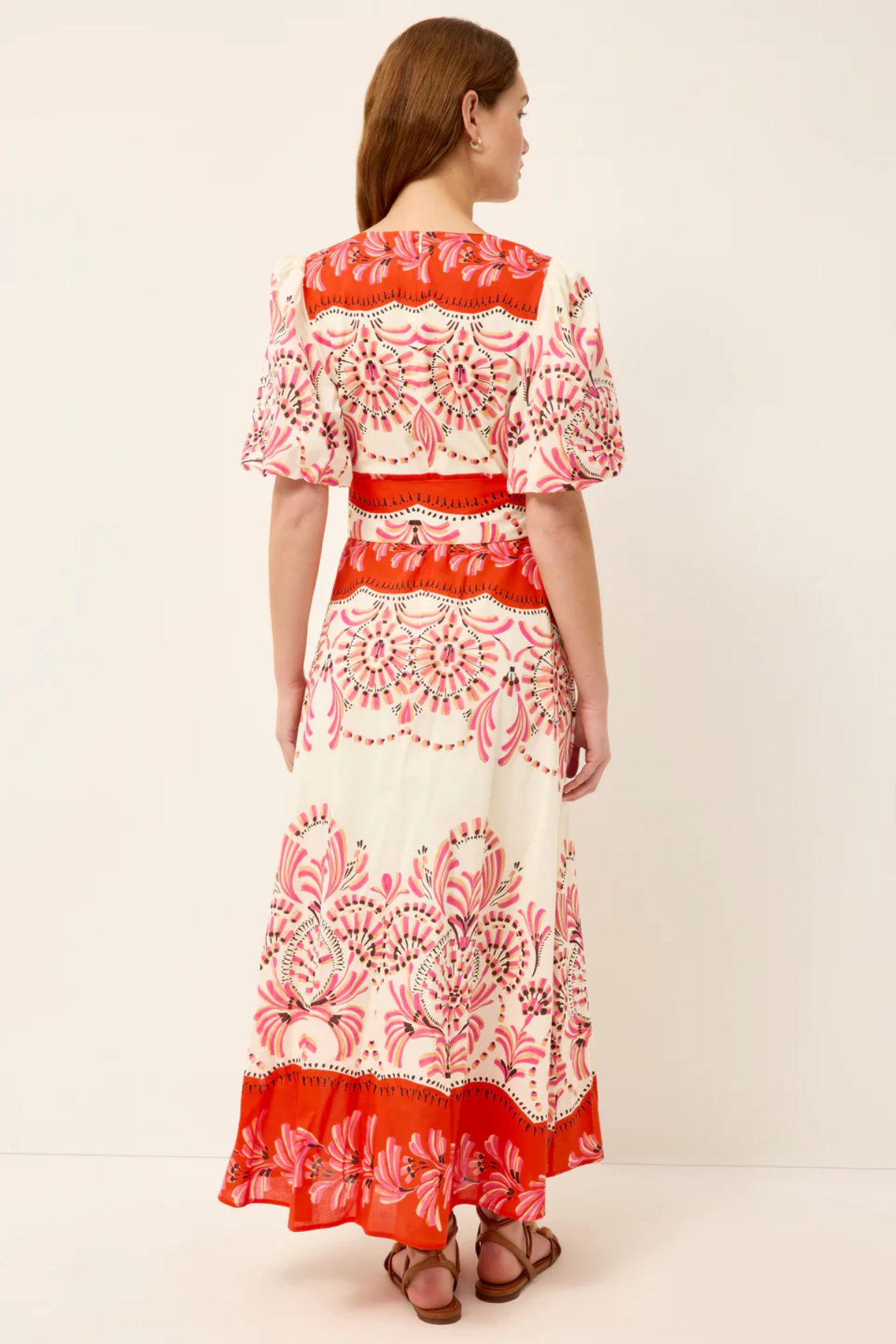 Woman wearing a red and white patterned dress on a plain background