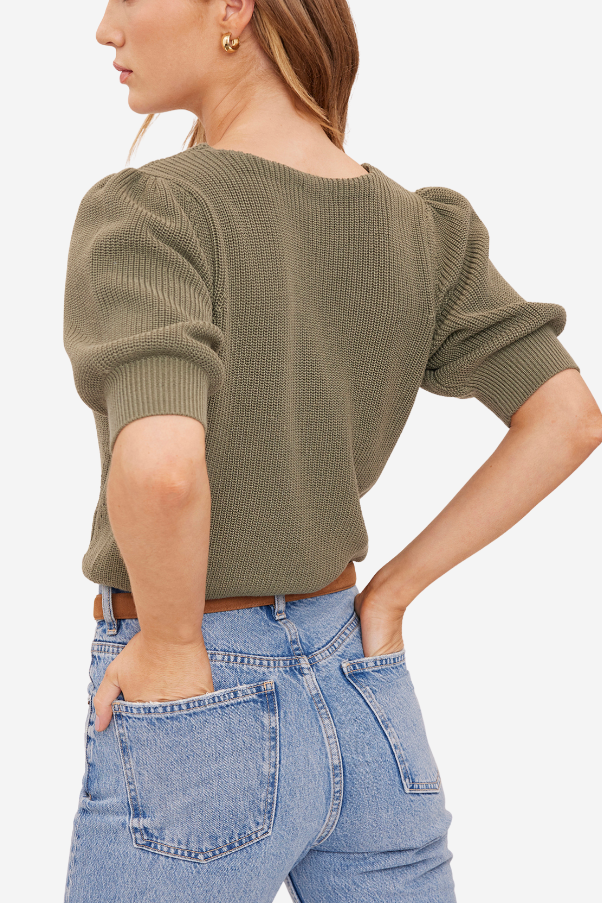 A woman wearing a ribbed short-sleeve knit top in olive green, paired with light blue jeans, shown from a side-back angle against a plain light background.