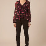 Woman wearing a floral blouse and black pants on a beige background