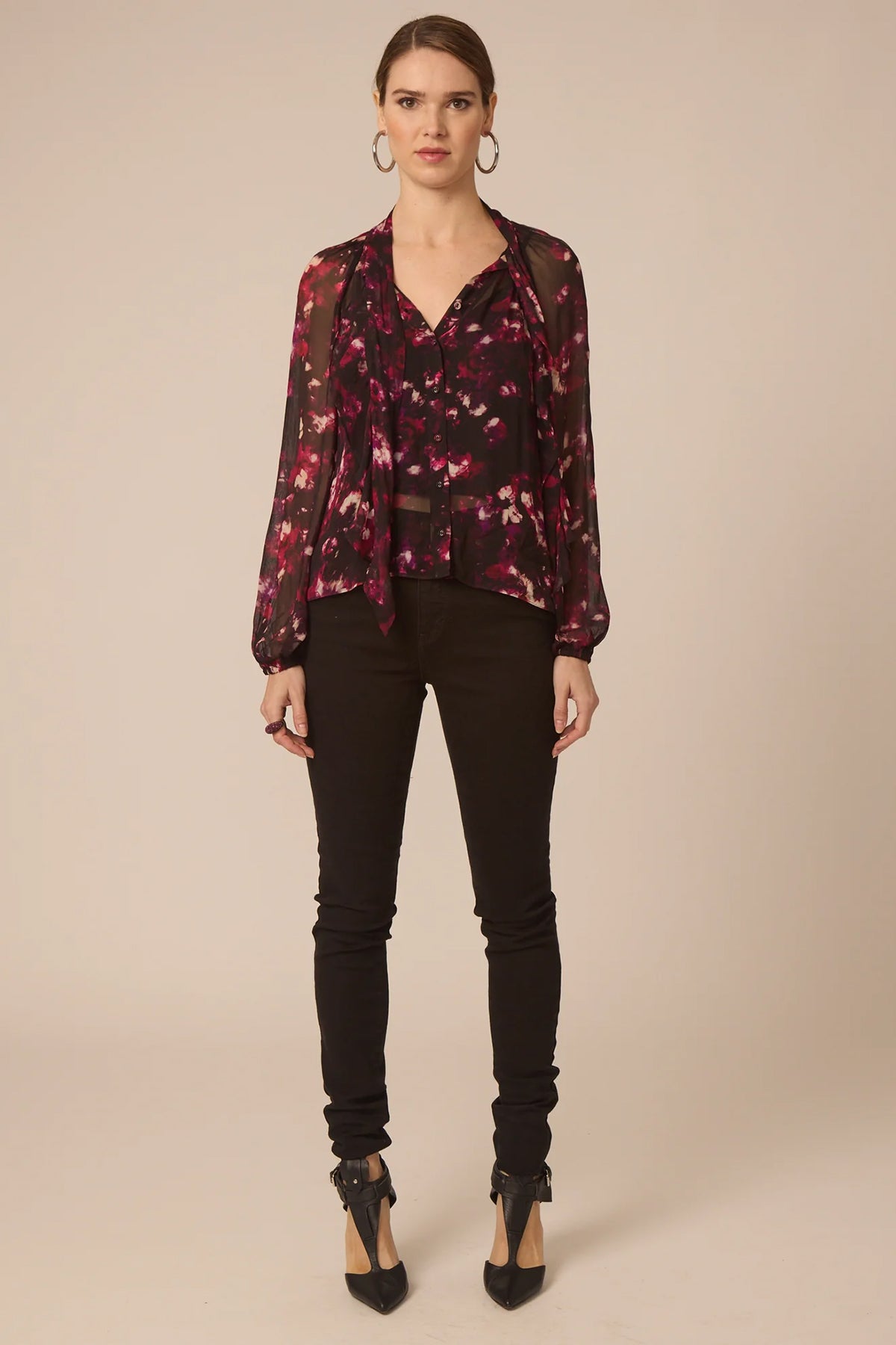 Woman wearing a floral blouse and black pants on a beige background