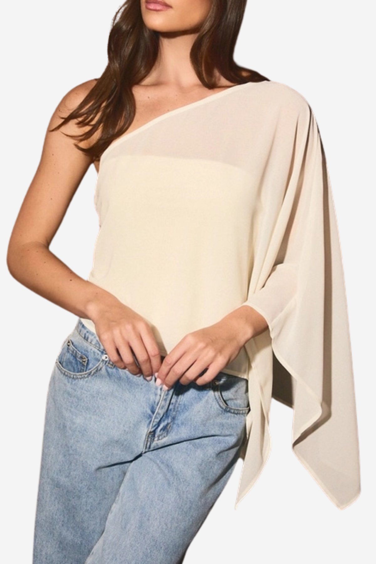 A woman wearing a light beige one-shoulder draped top and light blue jeans, shown from the neck down against a plain white background.