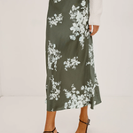 Person wearing a green floral skirt on a white background