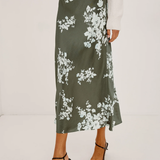 Person wearing a green floral skirt on a white background