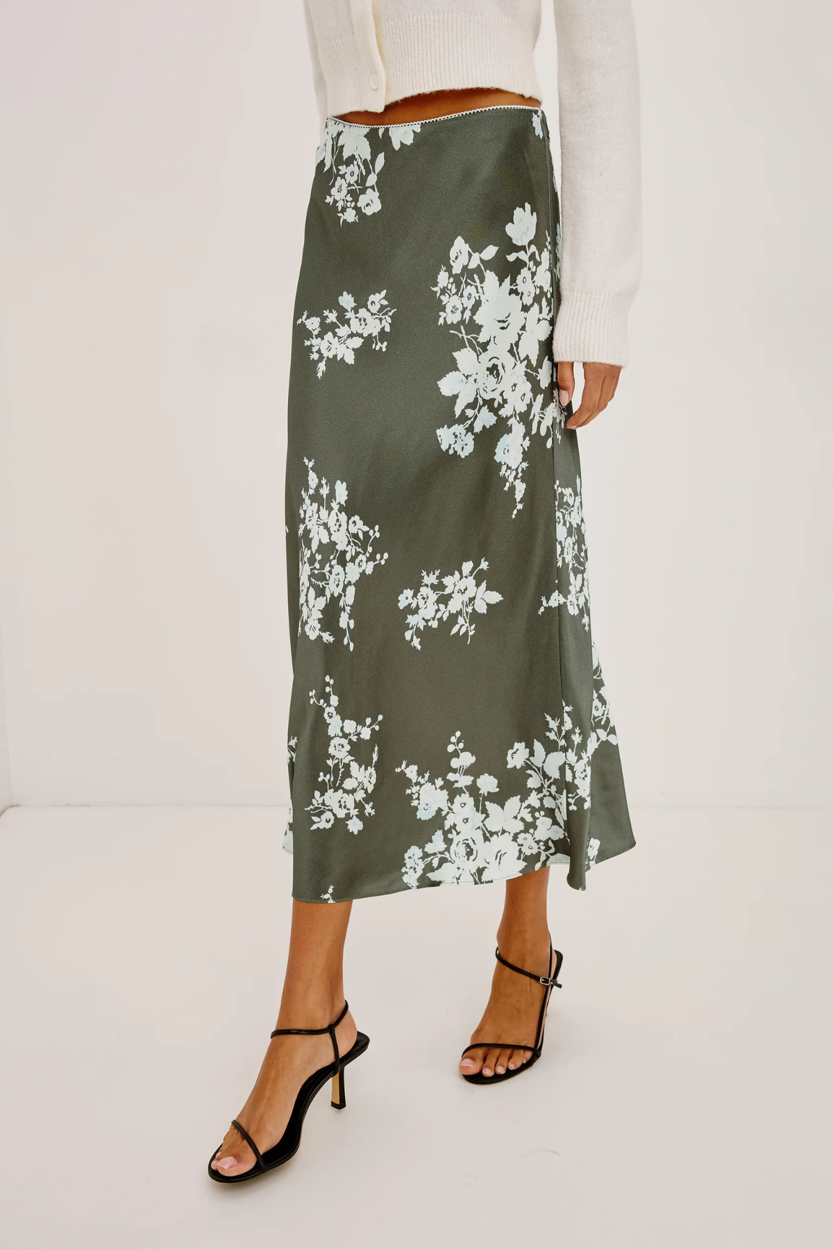 Person wearing a green floral skirt on a white background