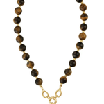 A beaded necklace featuring round brown and black tiger's eye beads with gold spacer rings, connected by a gold chain with a gold-tone pendant.