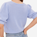 A woman wearing a light blue ribbed knit sweater with puffed elbow-length sleeves, shown from the back against a plain light background.