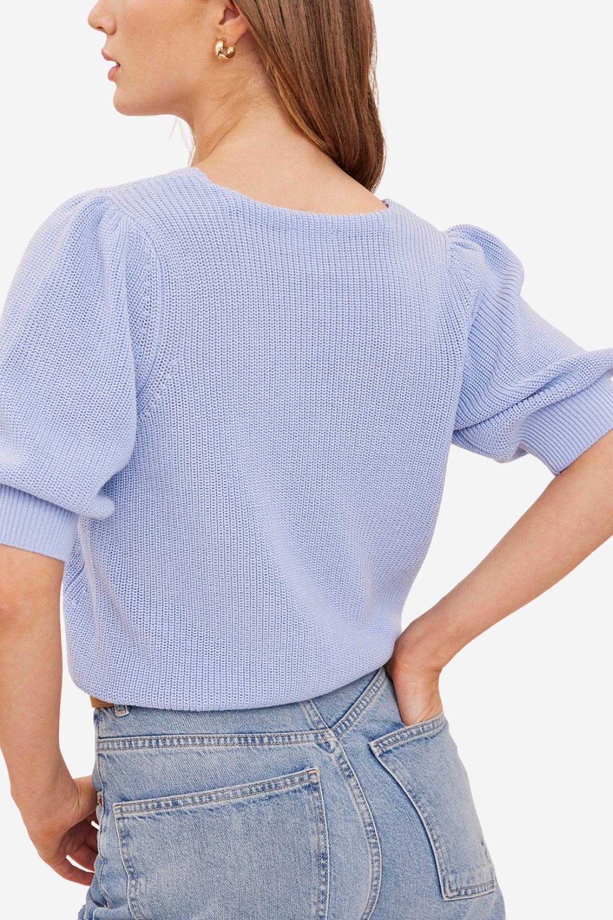 A woman wearing a light blue ribbed knit sweater with puffed elbow-length sleeves, shown from the back against a plain light background.