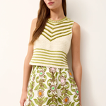Woman wearing a green and white patterned sleeveless top with a floral skirt against a white background