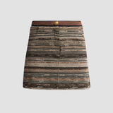 A mini skirt with a textured, woven horizontal stripe pattern in shades of brown, beige, and gray, featuring a contrasting dark brown waistband with a single gold button.