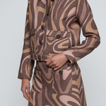 Model wearing a cropped printed jacket featuring a textured neutral-toned pattern with a modern tailored silhouette.