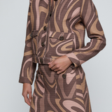 Model wearing a cropped printed jacket featuring a textured neutral-toned pattern with a modern tailored silhouette.