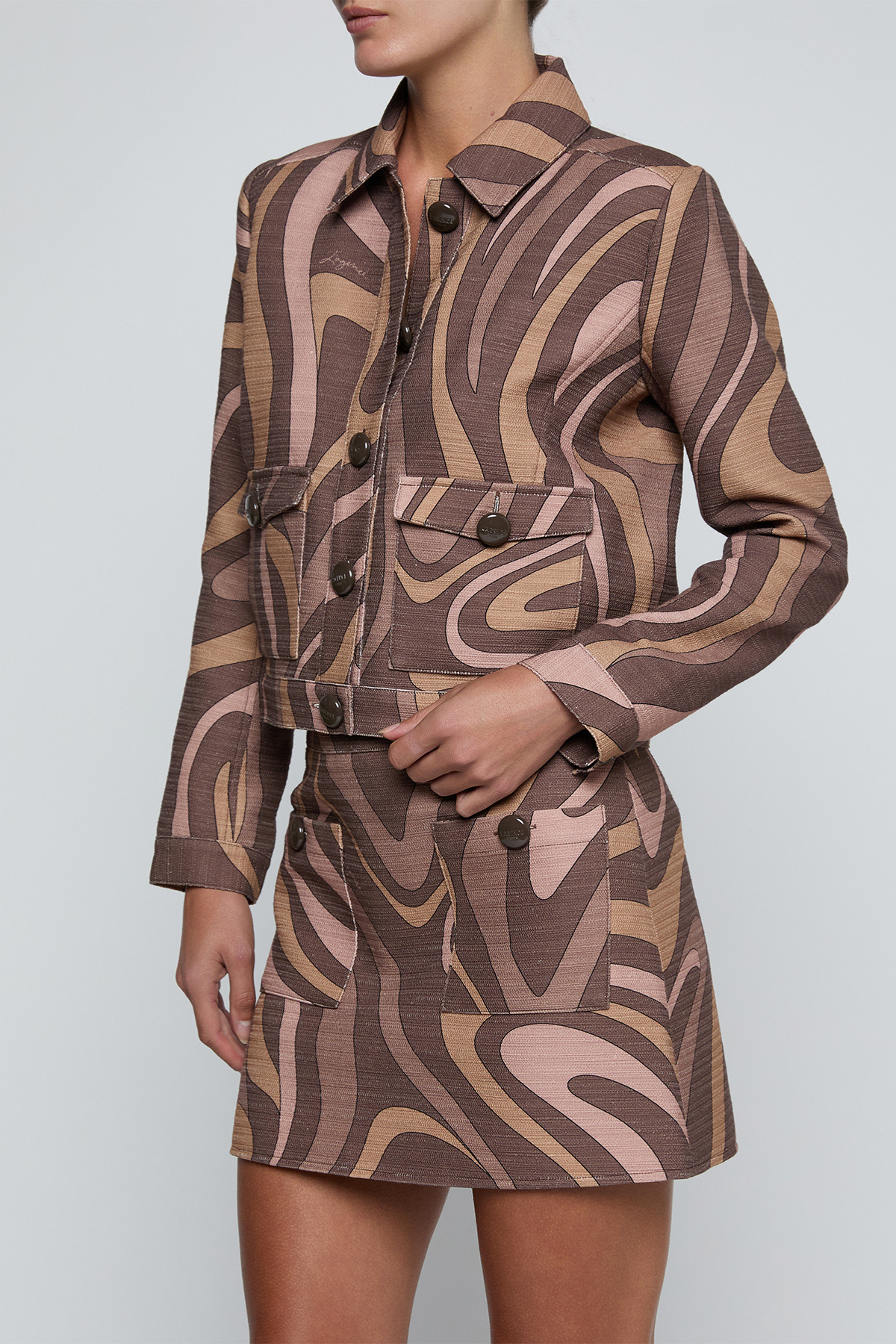 Model wearing a cropped printed jacket featuring a textured neutral-toned pattern with a modern tailored silhouette.