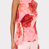 Woman wearing a sleeveless pink top with red floral pattern on a plain background