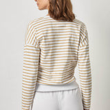 Woman wearing a striped long-sleeve top and white pants on a plain background