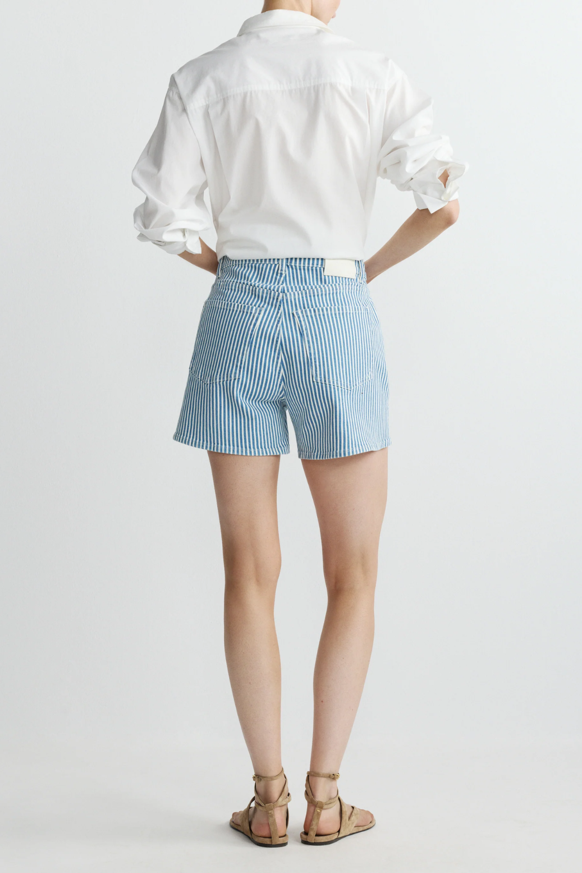 back of woman in stripe denim shorts on white background 