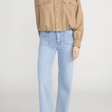 Person wearing a beige shirt with brown collar and light blue jeans on a white background