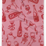 A pink waffle-weave kitchen towel featuring a repeating red pattern of champagne bottles, wine glasses, and hands holding glasses.
