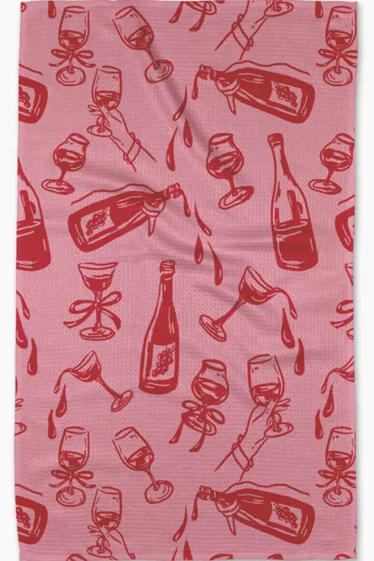 A pink waffle-weave kitchen towel featuring a repeating red pattern of champagne bottles, wine glasses, and hands holding glasses.