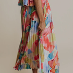 Person wearing a colorful floral dress against a plain background