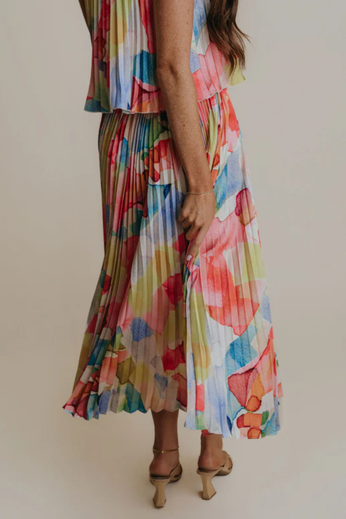 Person wearing a colorful floral dress against a plain background