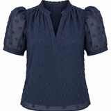 A navy blue short-sleeve blouse with puff sleeves, a ruffled split neckline, and a textured polka-dot pattern, shown against a plain white background.