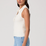 Woman wearing a white sleeveless top and light blue jeans on a plain background