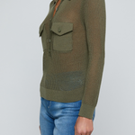 Model wearing a green knit button front sweater top with jeans on an off white background.