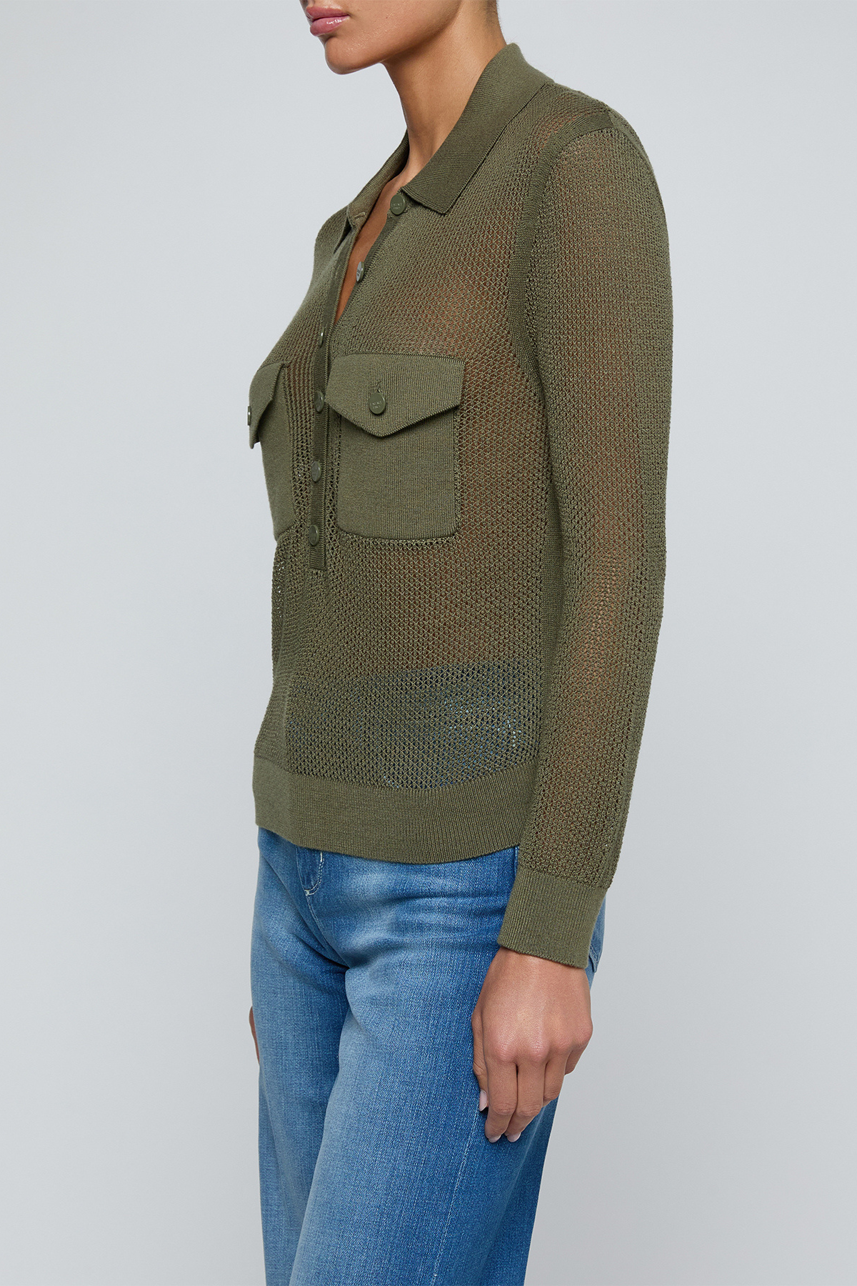 Model wearing a green knit button front sweater top with jeans on an off white background.
