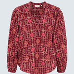 A long-sleeve blouse with a red, pink, and gold geometric pattern, displayed flat against a light gray background.