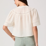 Woman wearing a white blouse with puffed sleeves on a plain background