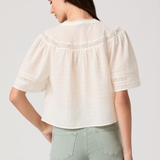 Woman wearing a white blouse with puffed sleeves on a plain background