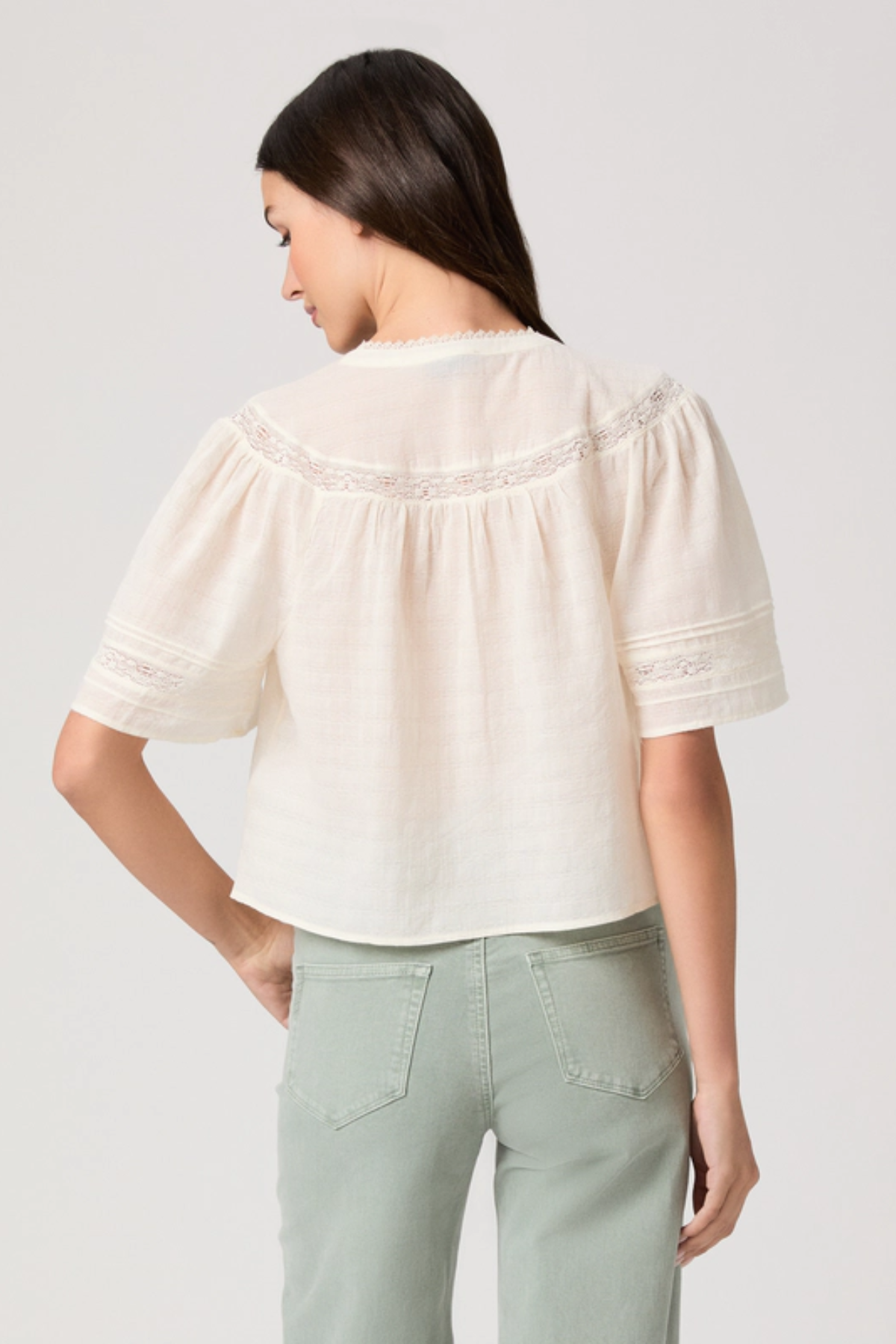 Woman wearing a white blouse with puffed sleeves on a plain background