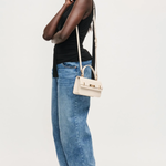Woman wearing a black top and blue jeans with a white handbag on a white background