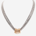 A silver-toned multi-strand chain necklace with a central cluster of textured gold-toned rings, displayed on a light gray background.