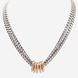 A silver-toned multi-strand chain necklace with a central cluster of textured gold-toned rings, displayed on a light gray background.