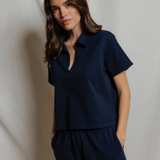 Woman wearing a navy blue outfit against a plain background