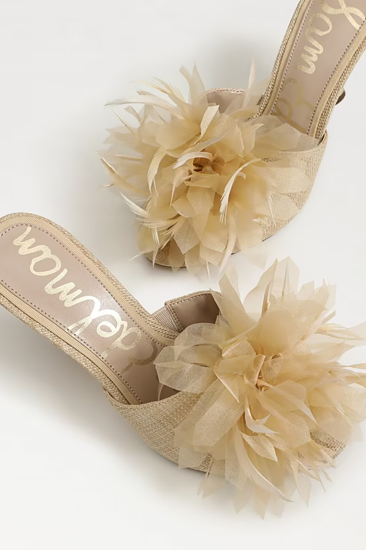 Beige high-heeled shoes with floral details on a white background