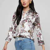 Woman wearing a floral blouse and jeans on a gray background