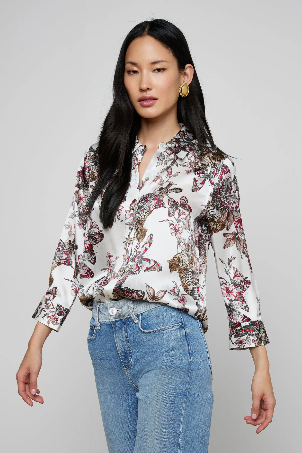 Woman wearing a floral blouse and jeans on a gray background