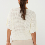 Woman wearing a white textured top and beige pants on a white background