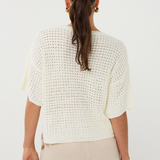 Woman wearing a white textured top and beige pants on a white background