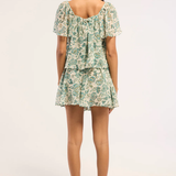 Woman wearing a floral top and skirt on a white background - back angle