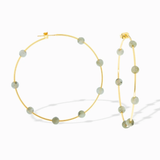 Gold hoop earrings with green beads on a white background
