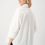 Woman wearing a white blouse with a high collar on a plain background