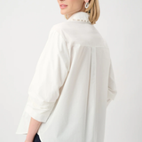 Woman wearing a white blouse with a high collar on a plain background